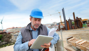 Construction manager controlling building site with plan